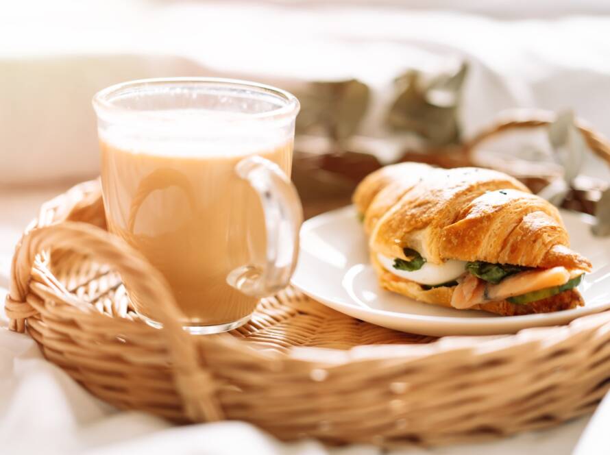 Breakfast in bed with croissant and coffee on tray
